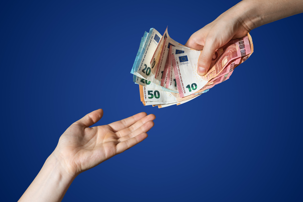 Hand giving some money euros isolated. Blue background